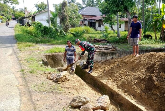 Babinsa Keumireu Bantu Warga Bersihkan Saluran Air