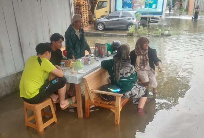 Korban Banjir Makan di Atas Genangan Air